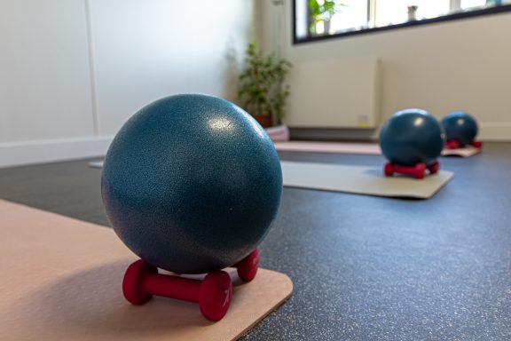 Blauwe fitnessballen op dumbbells met matten in een lichte ruimte.
