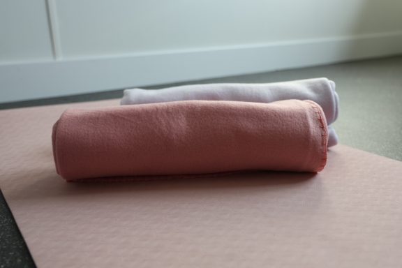 Een rose en een paars kleed liggen op een roze pilatesmat.